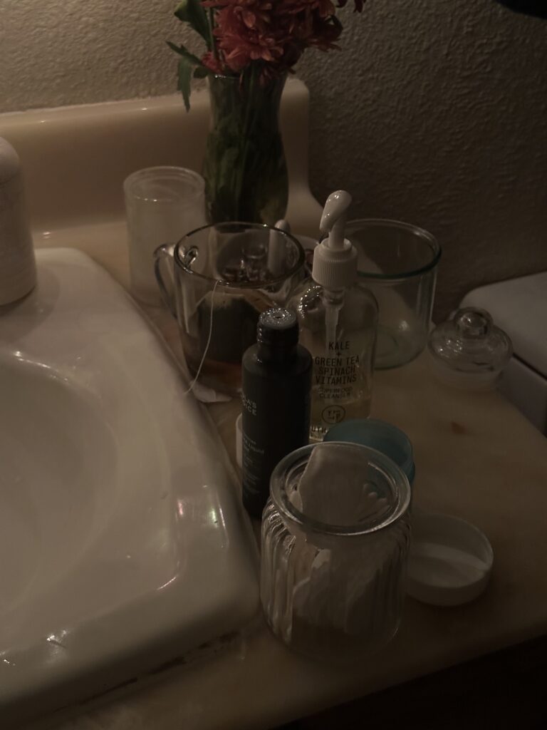 skincare products sitting on bathroom counter with tea mug, clean girl