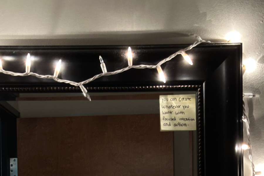 fairy lights around a mirror with a sticky note in the corner