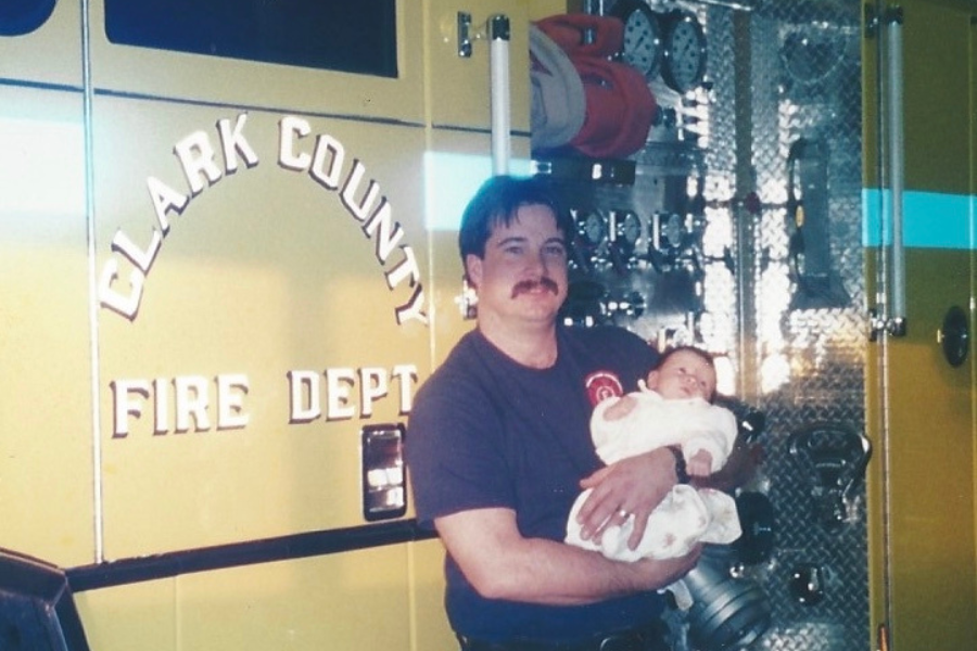 Picture of a man and his baby in front of a fire truck, todd